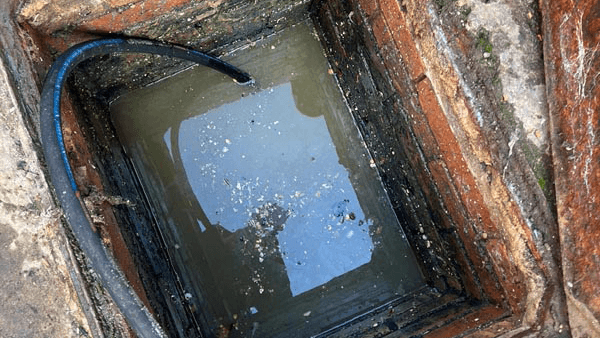 A photo of a badly blocked drain with a drain jetter ready to start unblocking